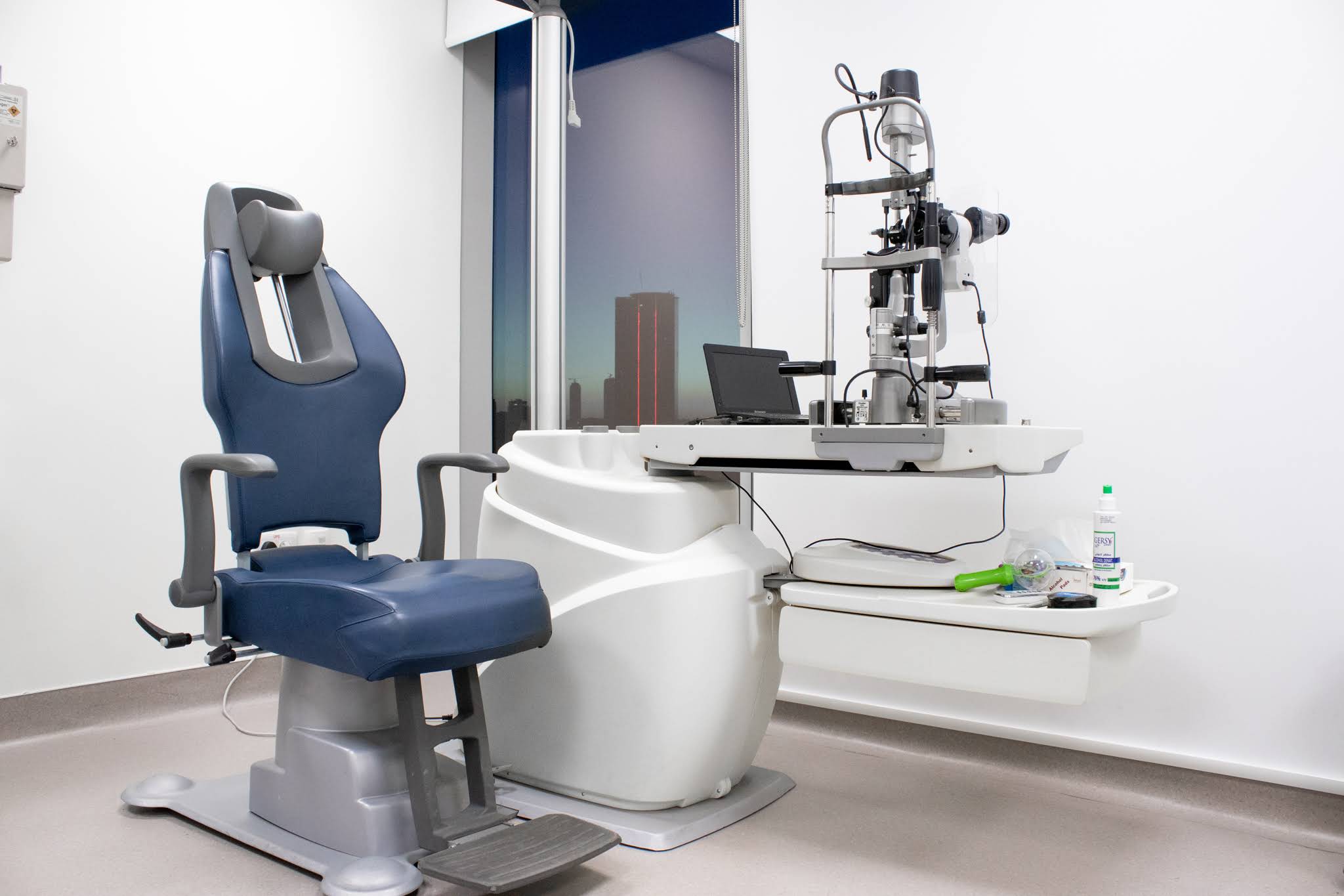 Modern ophthalmology examination room with slit lamp and patient chair.