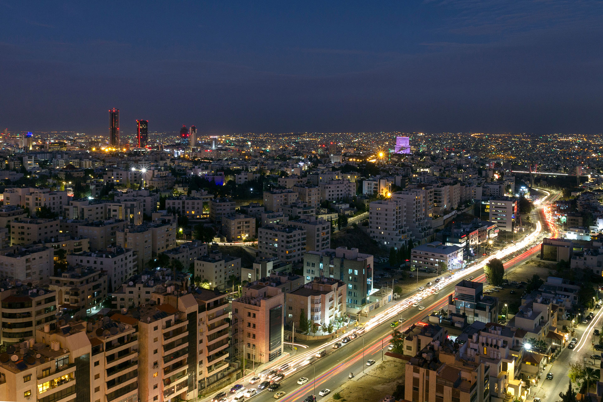 Panoramic night view of Amman city with illuminated streets and modern towers in Jordan.