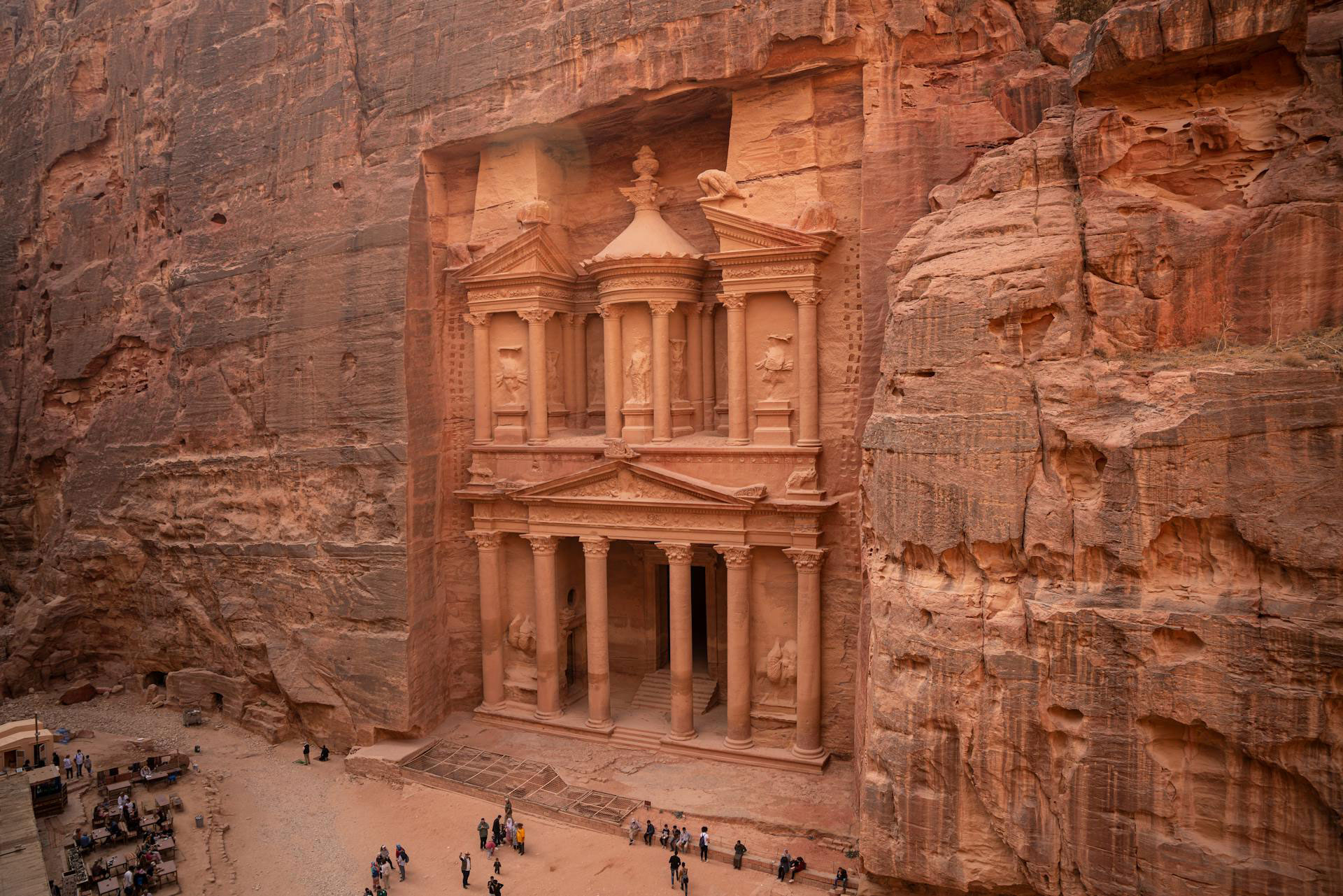 Aerial view of The Treasury (Al-Khazneh) in Petra, Jordan, with tourists at the entrance.