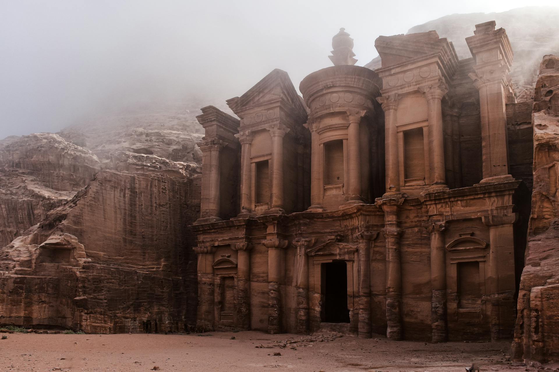 The Monastery (Ad-Deir) in Petra, Jordan, surrounded by mist and carved into sandstone cli