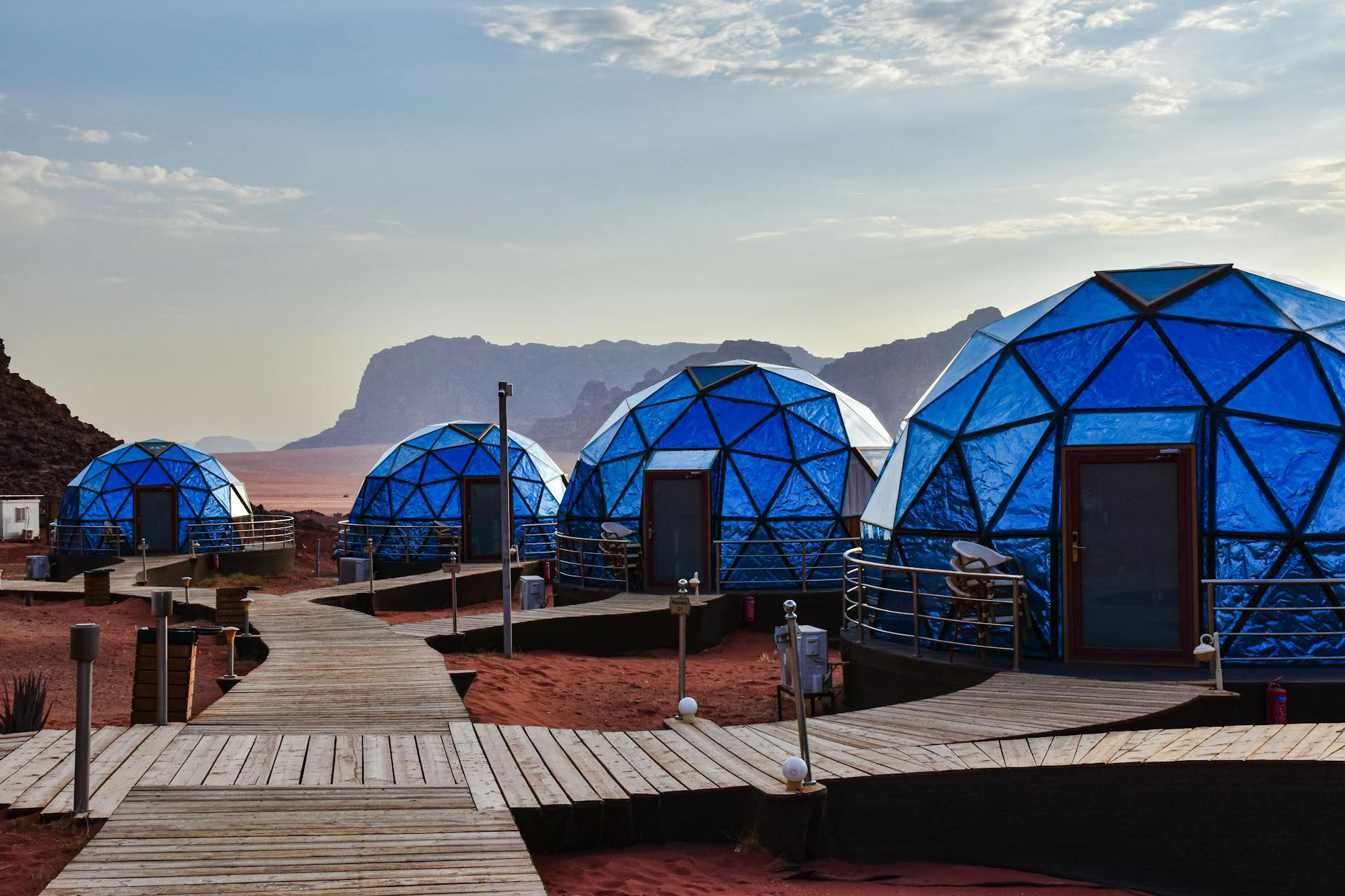 Luxury bubble dome tents in Wadi Rum desert, Jordan, with wooden walkways and mountain views.