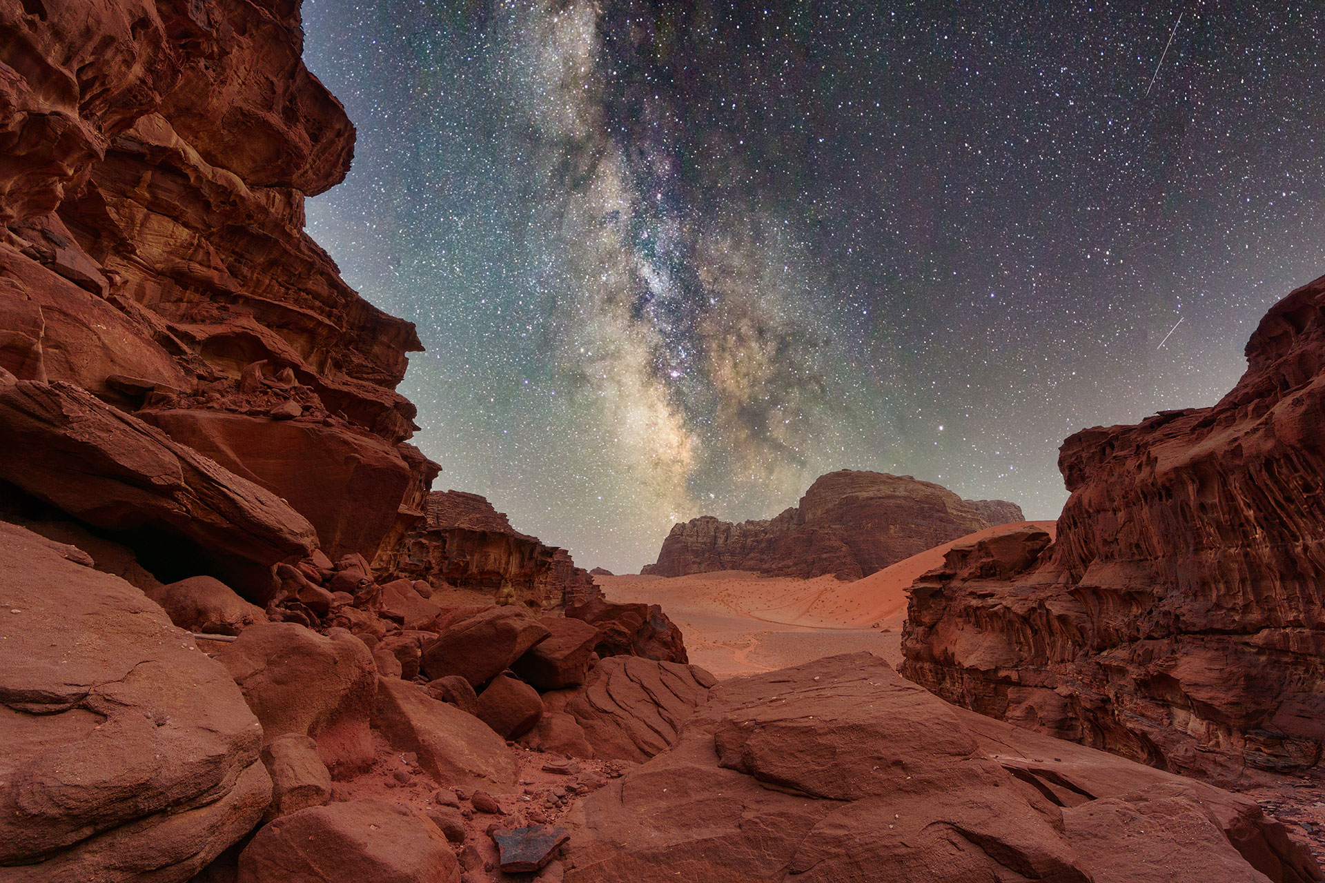 Wadi Rum desert in Jordan at night with the Milky Way galaxy visible in the starry sky.